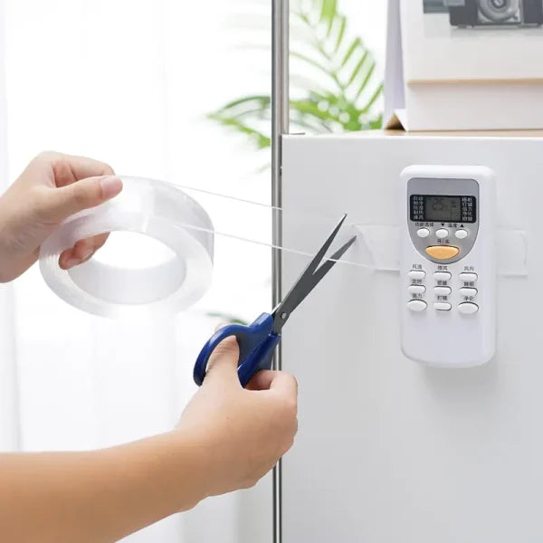 Person cutting clear tape with scissors on a white appliance.